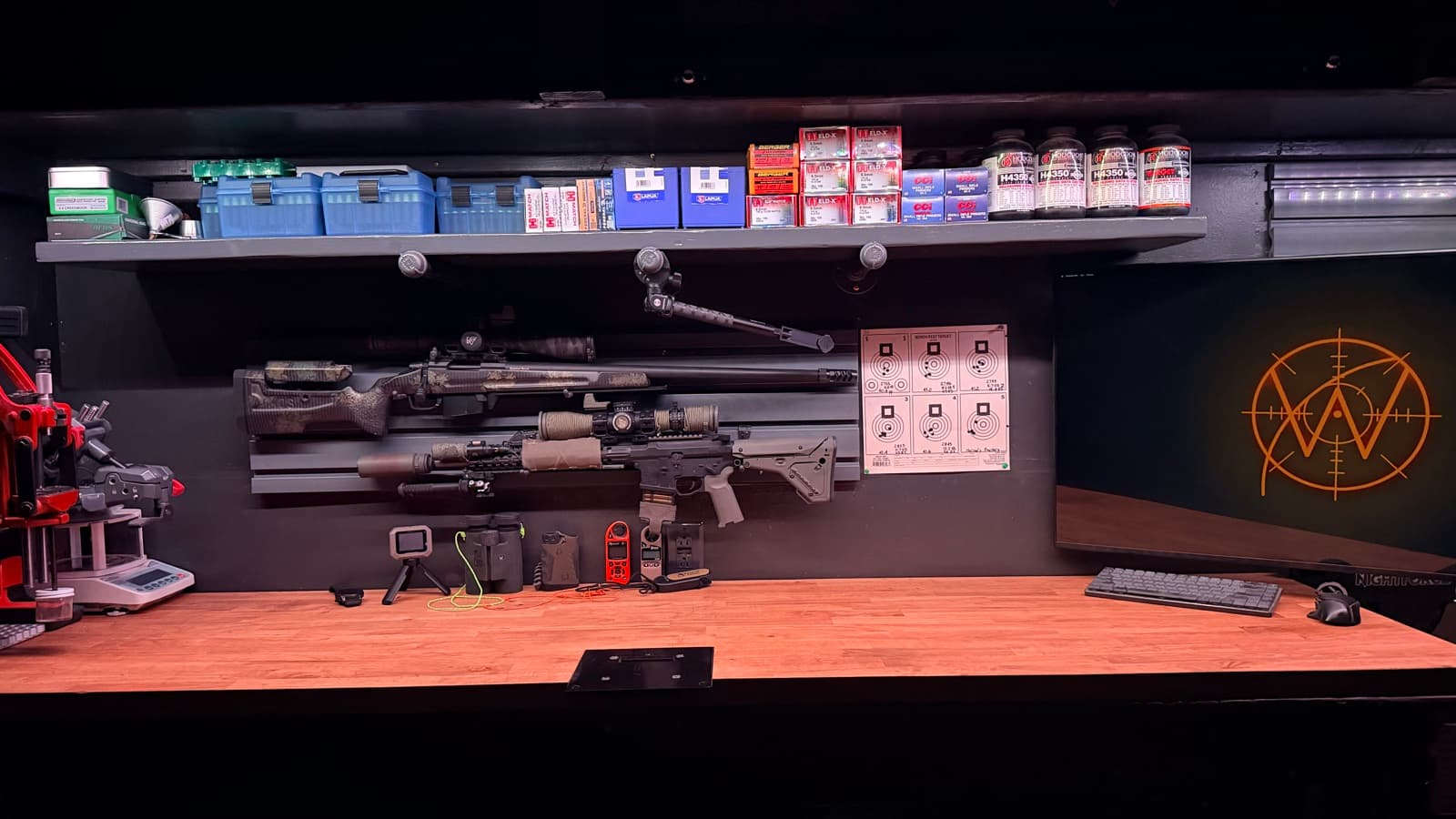 The reloading bench where Wrist Dope is built: rifles, a reloading press, a chronograph, and the Wrist Dope mark on the wall